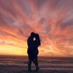 happy-couple-kissing-on-beach-at-sunset-awaken