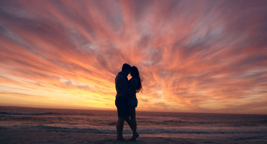 happy-couple-kissing-on-beach-at-sunset-awaken