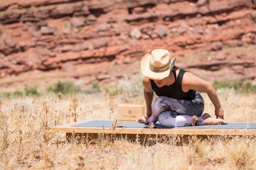 woman stretches her hips in a seated yoga pose - yogatoday