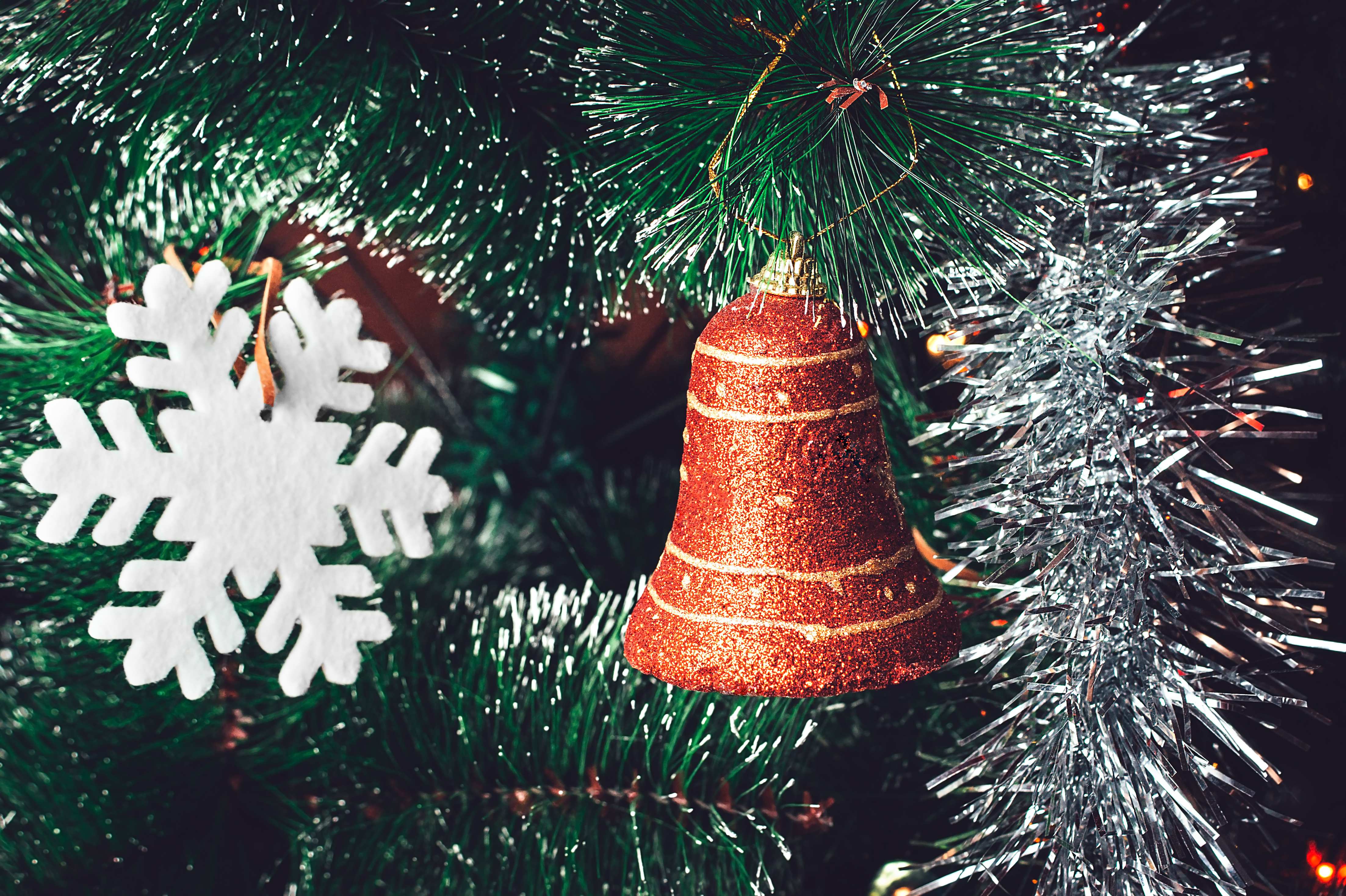 Christmas Tree Decorations: Red Orange Bell, White Snowflake, Shining Silver Tinsel on Green Needles with White Tips. Happy New Year and Christmas Concept.