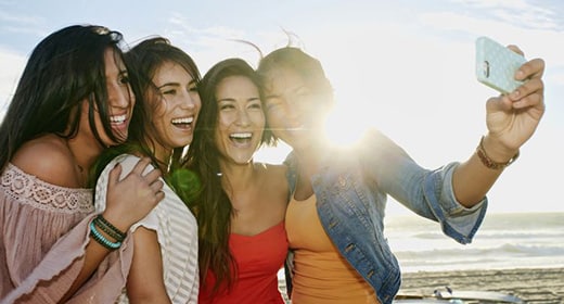 women-taking-pictures-together-on-beach-awaken