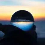 person-holding-glass-globe-near-ocean-awaken