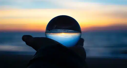 person-holding-glass-globe-near-ocean-awaken